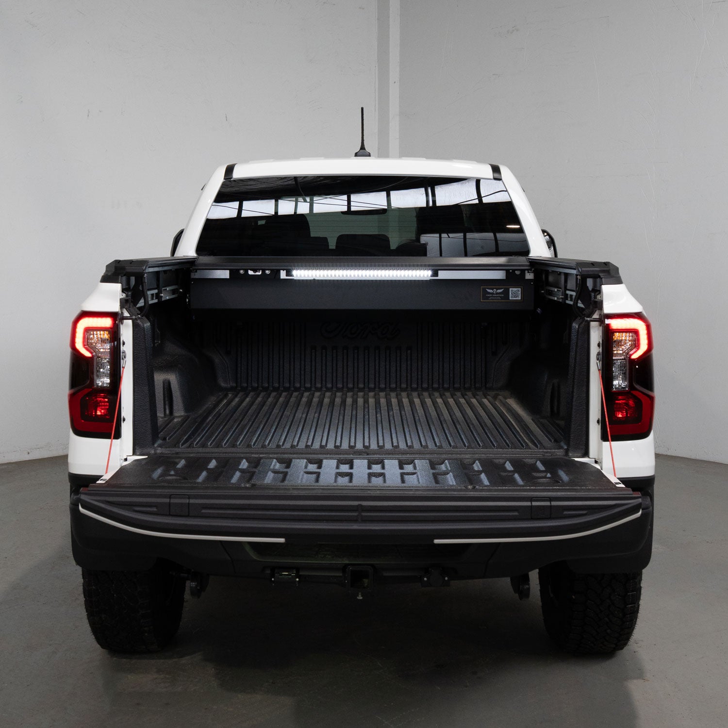 Back view of a white pickup truck with an open bed in a garage.