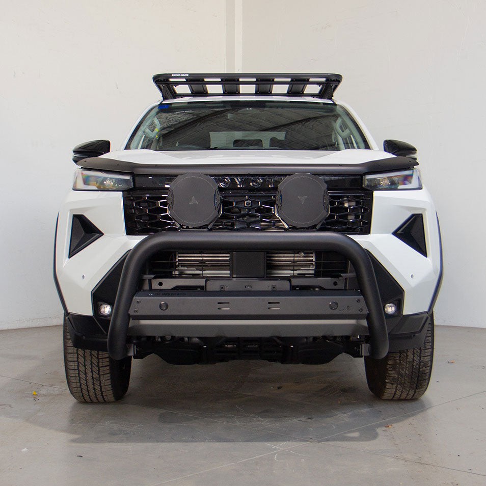 White SUV with black front bumper and roof rack on a gray floor.