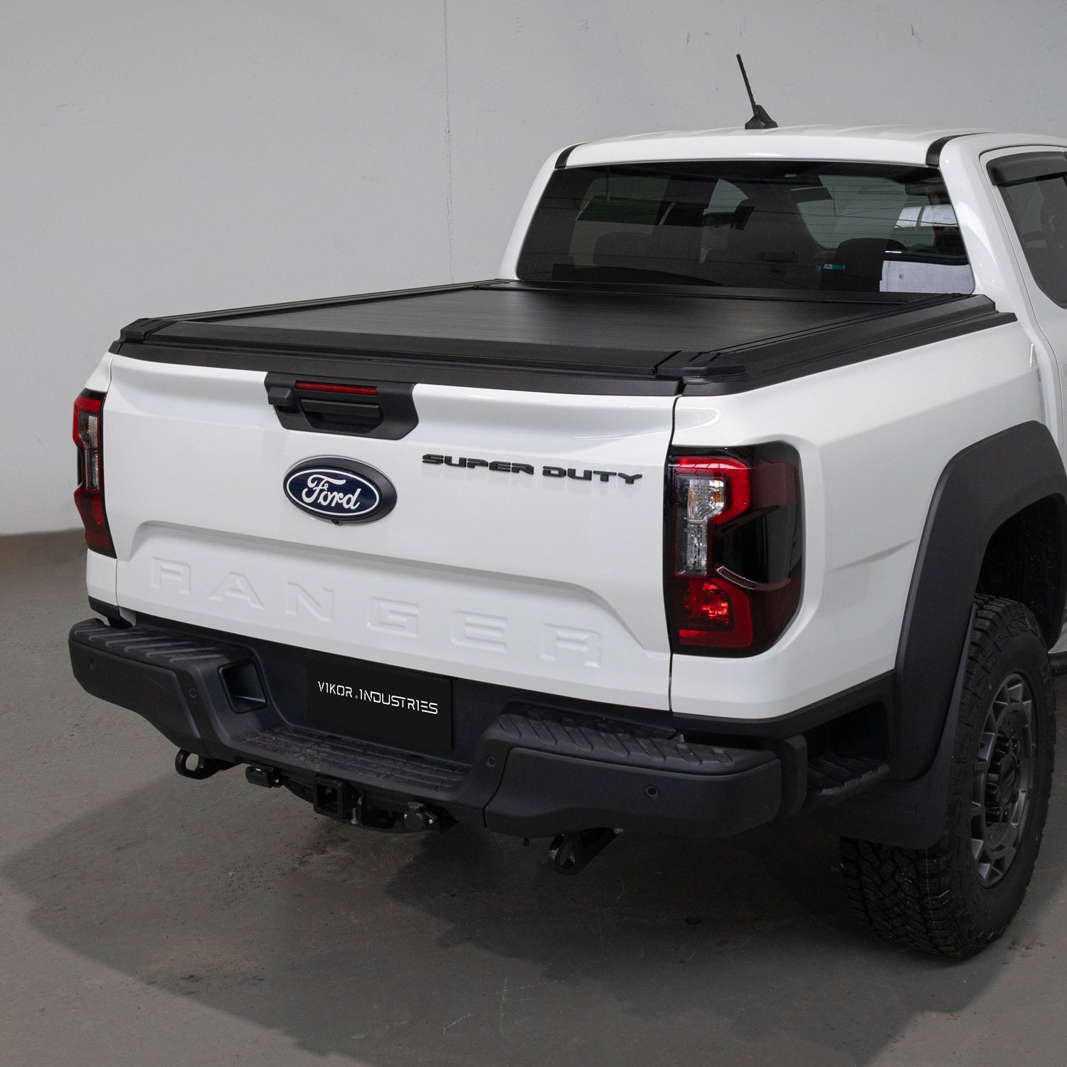 White Ford Super Duty truck with a black tonneau cover in a studio setting