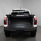 Back view of a white pickup truck with an open bed in a garage.