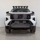 White SUV with black front bumper and roof rack on a gray floor.