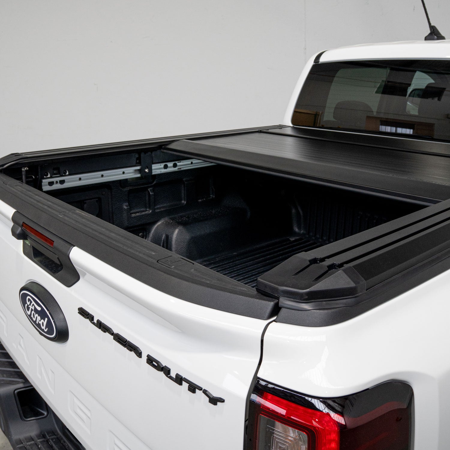 White Ford Super Duty truck with an open black tonneau cover on a white background