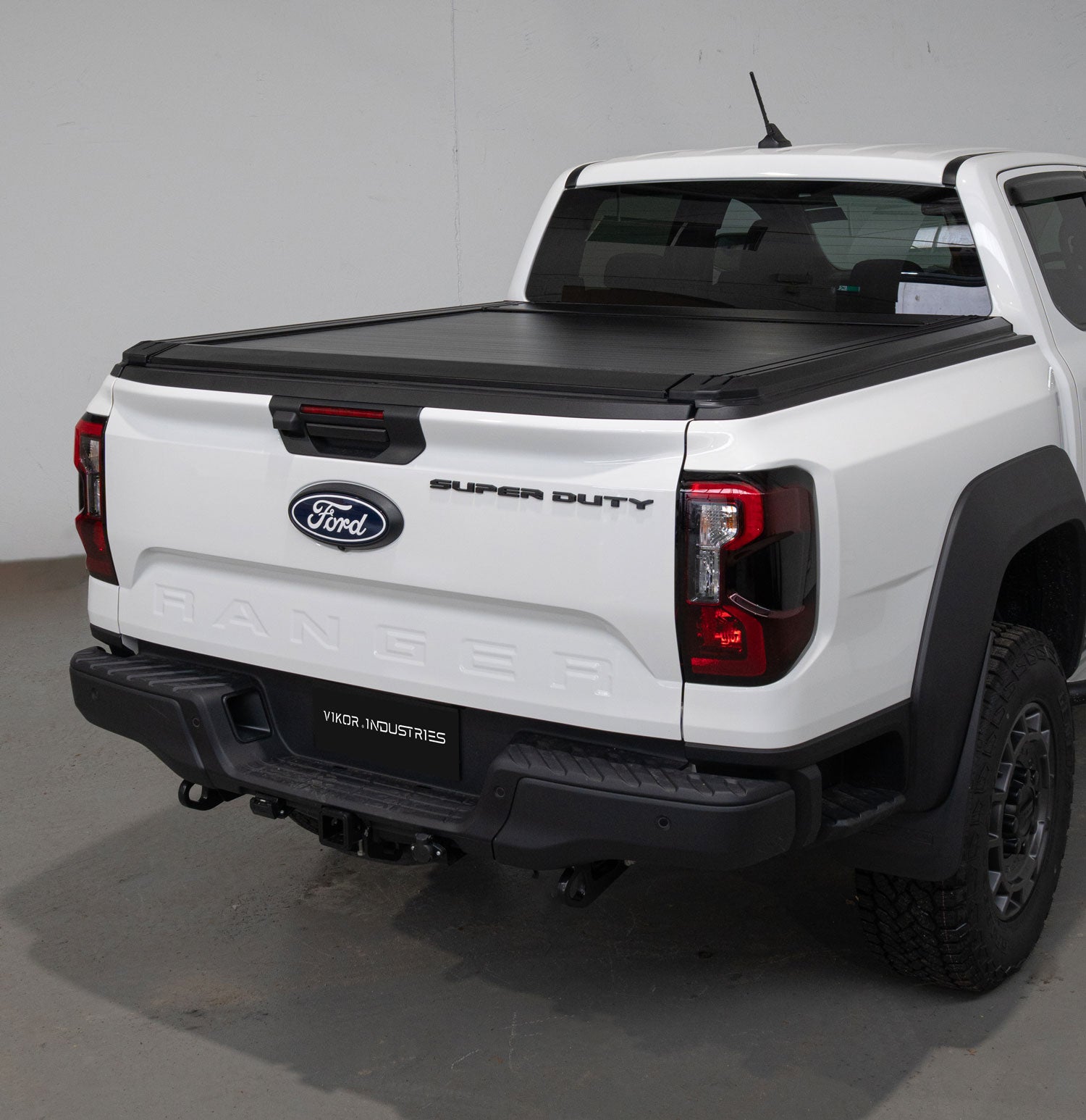 White Ford Super Duty truck with a black tonneau cover in a studio setting