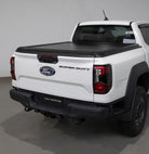 White Ford Super Duty truck with a black tonneau cover in a studio setting